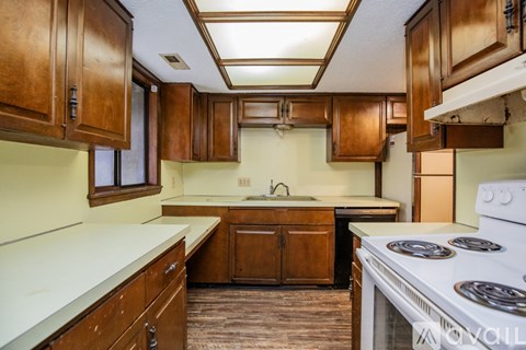 A kitchen with wooden cabinets and a white stove top oven.