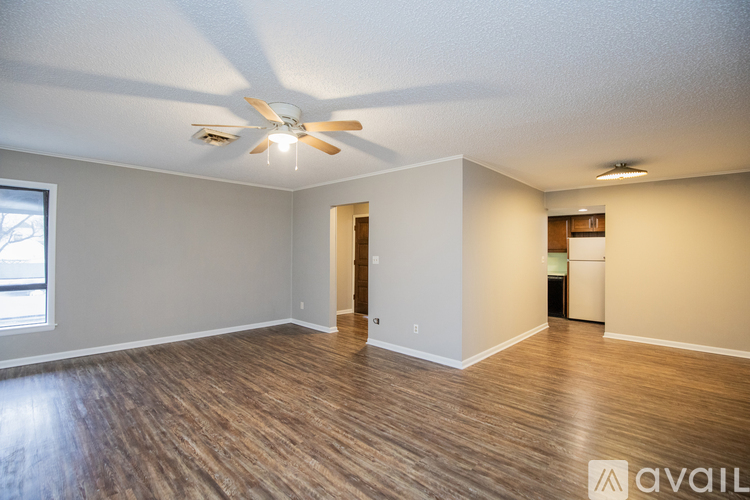 A spacious room with a ceiling fan and wooden flooring.