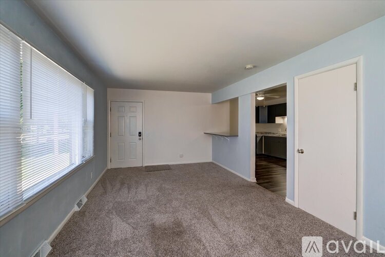 A room with a carpeted floor and a window with blinds.