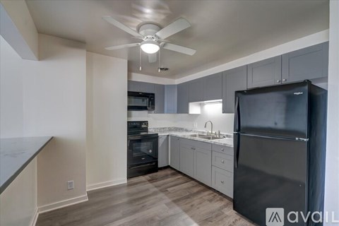 A kitchen with a black refrigerator and wooden floors.