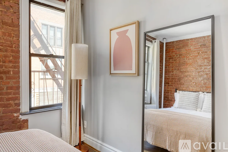 A bedroom with a bed, a lamp, a painting, and a mirror.