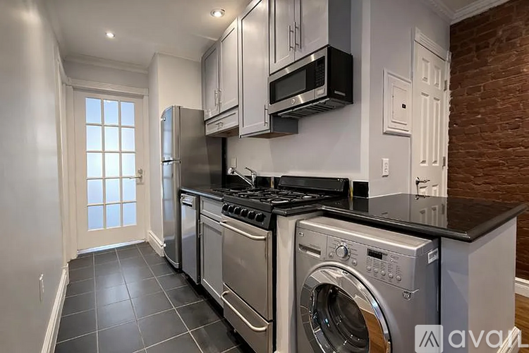 A modern kitchen with stainless steel appliances and a brick wall.