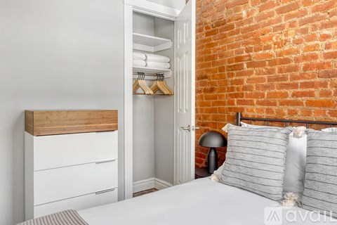 A bedroom with a white bed, a wooden headboard, and a white wardrobe with a glass door.