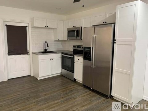 A kitchen with white cabinets and a stainless steel refrigerator.