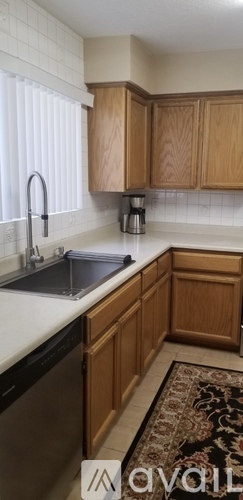 A kitchen with wooden cabinets and a black dishwasher.