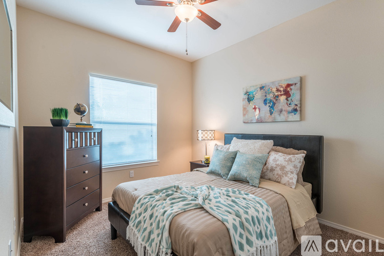 A bedroom with a bed, dresser, and ceiling fan.