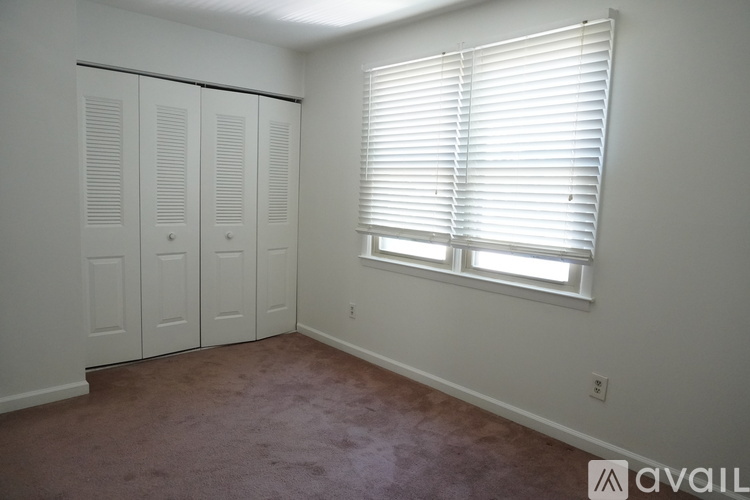A room with a window and a carpeted floor.