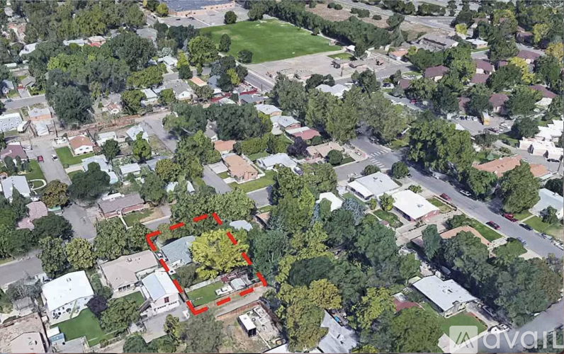 A bird's eye view of a residential area with a red outlined property in the foreground.
