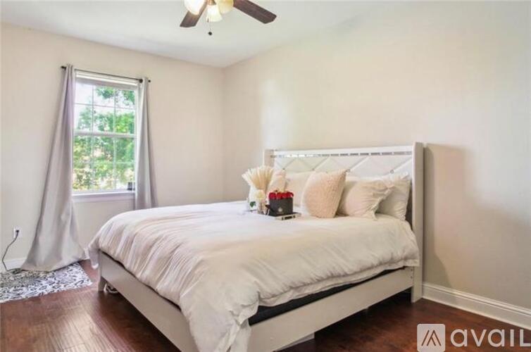 A bedroom with a white bed and a ceiling fan.