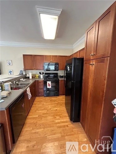 A kitchen with wooden cabinets and a black fridge.