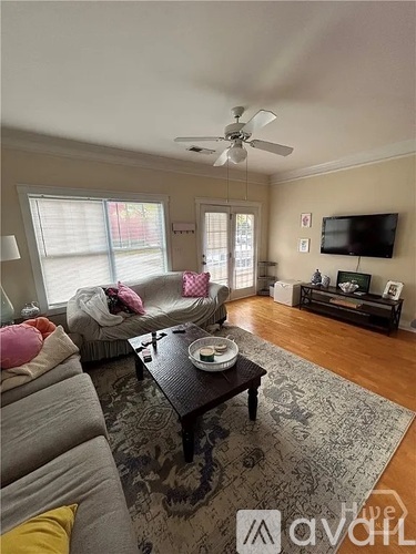 A living room with a grey couch, a black coffee table, and a flat screen TV mounted on the wall.