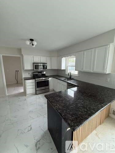 A kitchen with a black counter top and white cabinets.