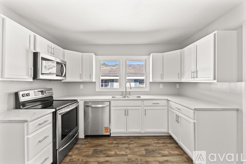 A kitchen with white cabinets and appliances.