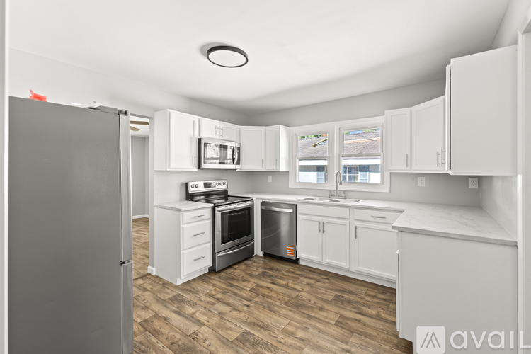 A kitchen with white cabinets and a wooden floor.