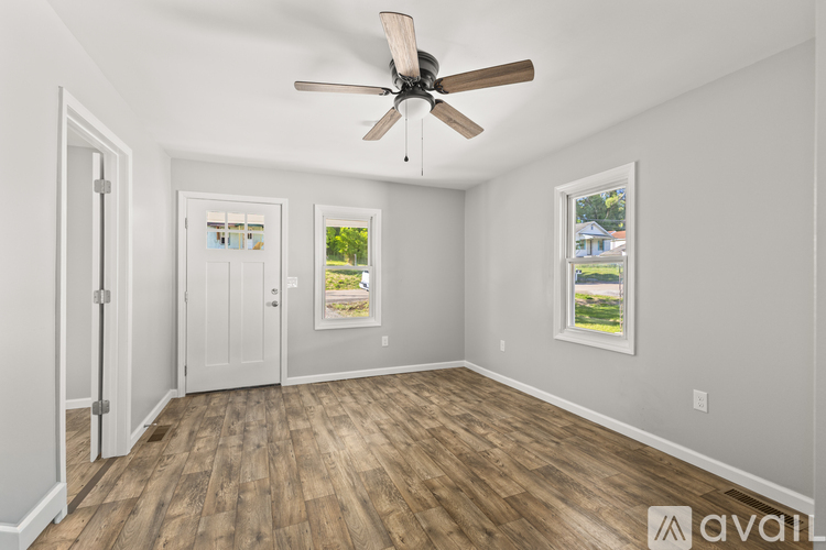 A room with a ceiling fan and wood flooring.