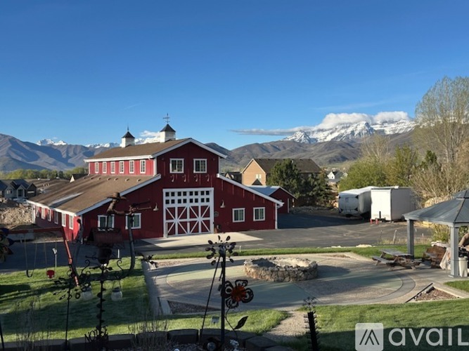 A red barn with a white garage door is in the foreground with mountains in the background.