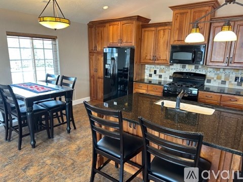 A kitchen with wooden cabinets and black chairs.