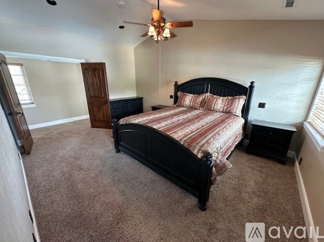A bedroom with a large bed and a ceiling fan.