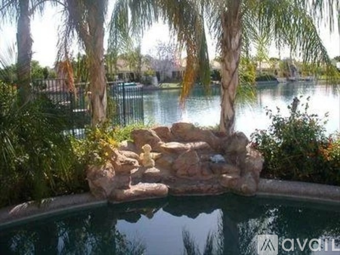 A pool with a rock formation in the middle and trees surrounding it.