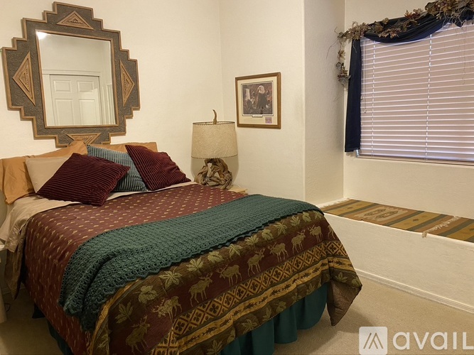 A bedroom with a bed covered in a patterned blanket and pillows.