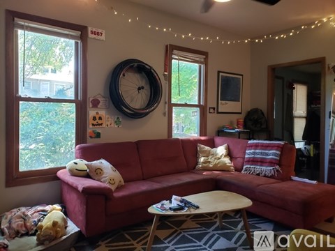 A red couch with pillows and a tire on the wall in a living room.