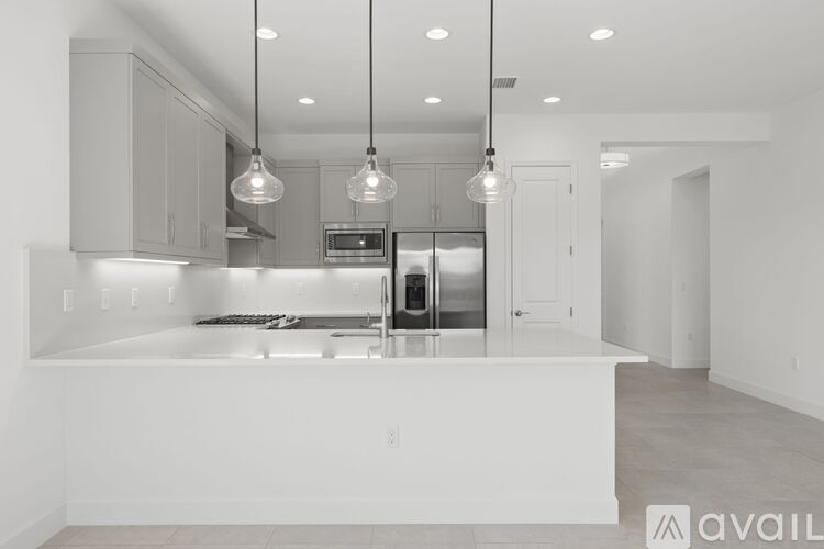 A modern kitchen with a white countertop and stainless steel appliances.