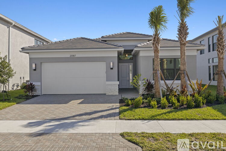 A modern house with a garage and palm trees in front.