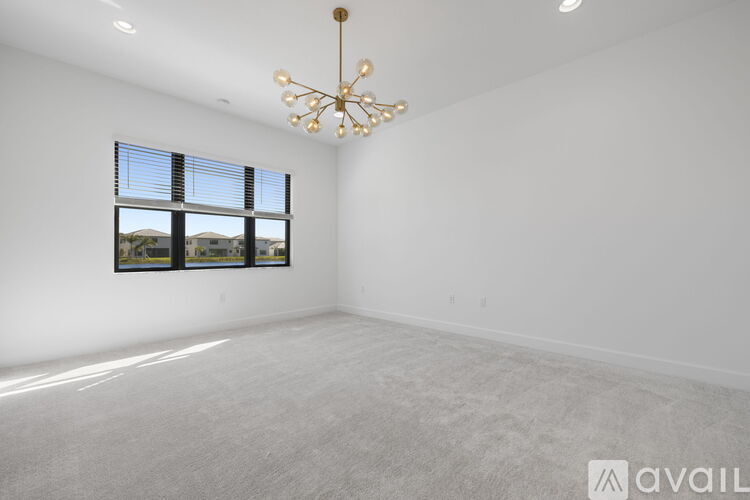 A spacious room with a large window and a chandelier hanging from the ceiling.