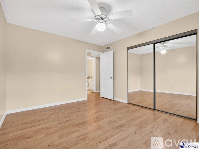 A room with a ceiling fan and mirrored door.