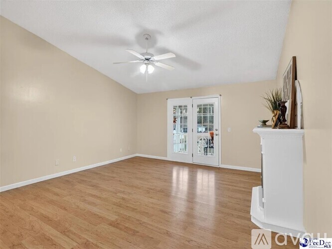 A spacious room with a ceiling fan and wooden flooring.