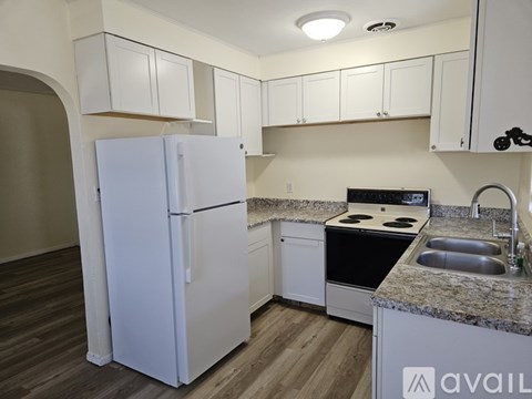 A kitchen with a white refrigerator and a granite countertop.