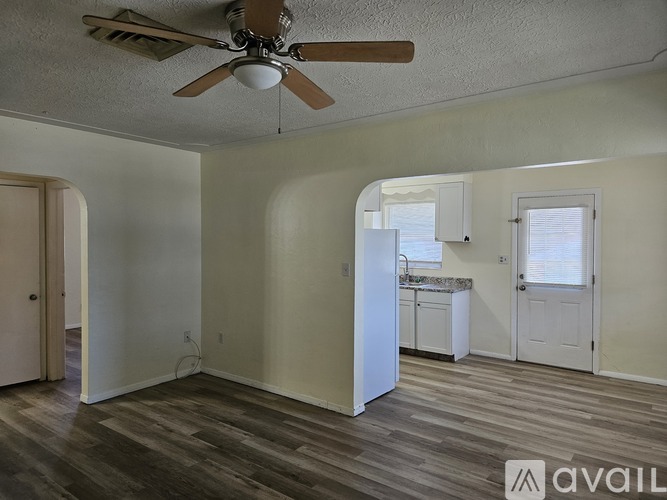 A room with a ceiling fan and wooden flooring.