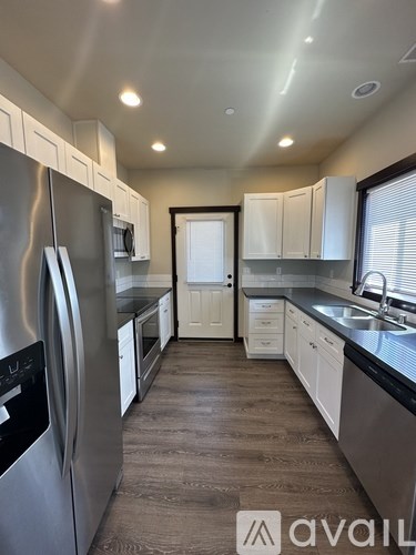 A kitchen with a refrigerator on the left and a sink on the right.