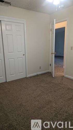 A room with a carpeted floor and two doors, one of which is open.