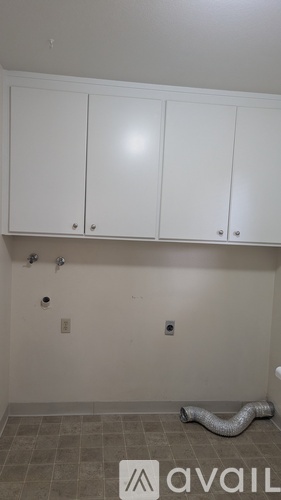 A room with white cabinets and a grey floor.