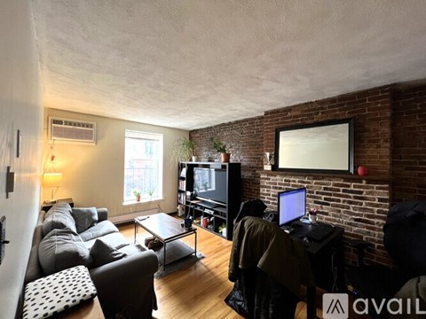 A person is sitting on a couch in a living room with a television and a flat screen monitor on the wall.