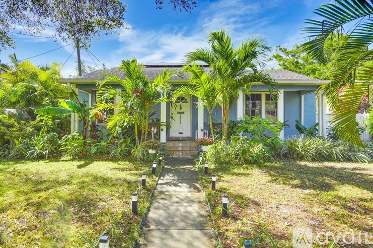 A house with a green lawn and trees in front.