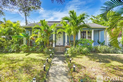 A house with a green lawn and trees in front.