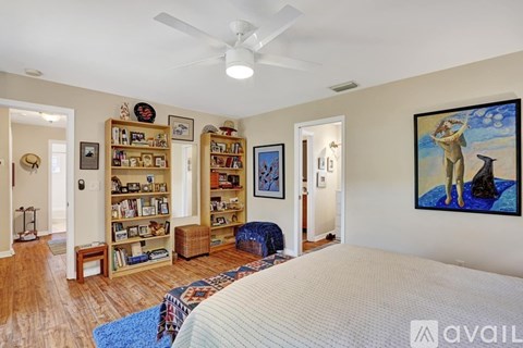 A bedroom with a large bed and a painting of a woman on the wall.