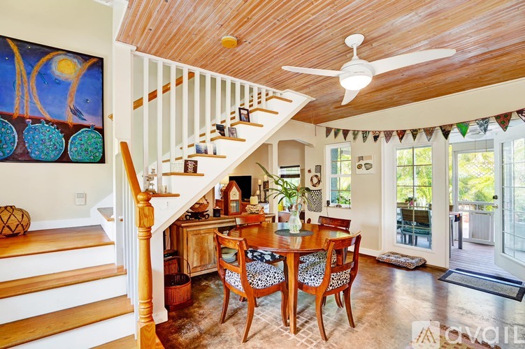 A wooden staircase with a white railing leads to a living room with a dining table and chairs.