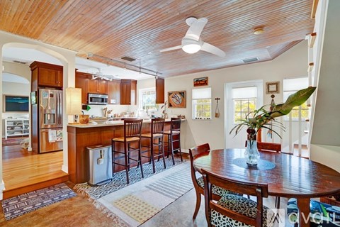 A kitchen with a wooden ceiling and a dining table with chairs.