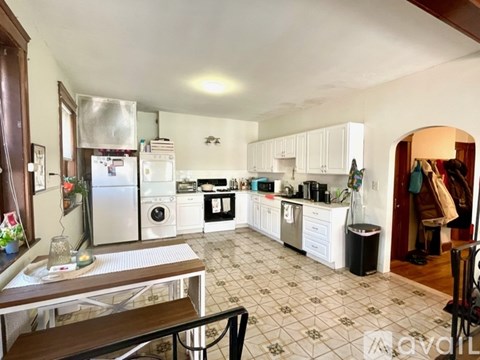 A kitchen with white cabinets and a tiled floor.