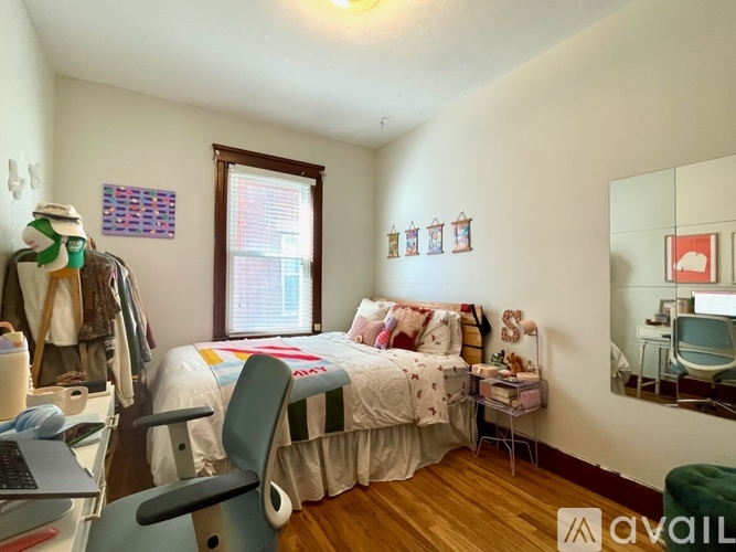 A bedroom with a bed, chair, and a laptop on a desk.