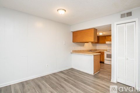A kitchen with white walls and wooden cabinets is available for rent.