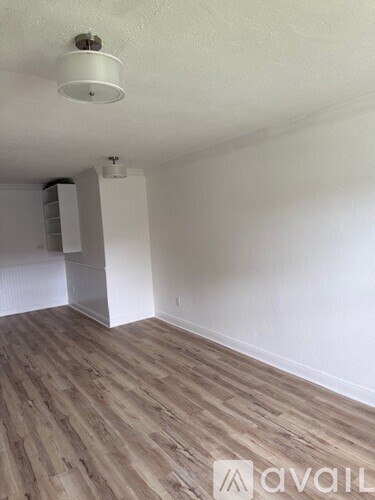 A room with wooden flooring and white walls.