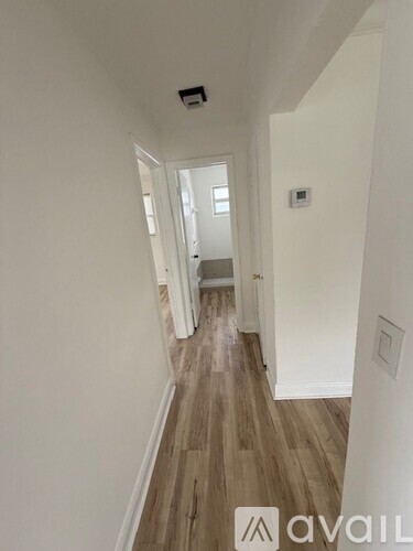 A hallway with wooden floors and white walls.