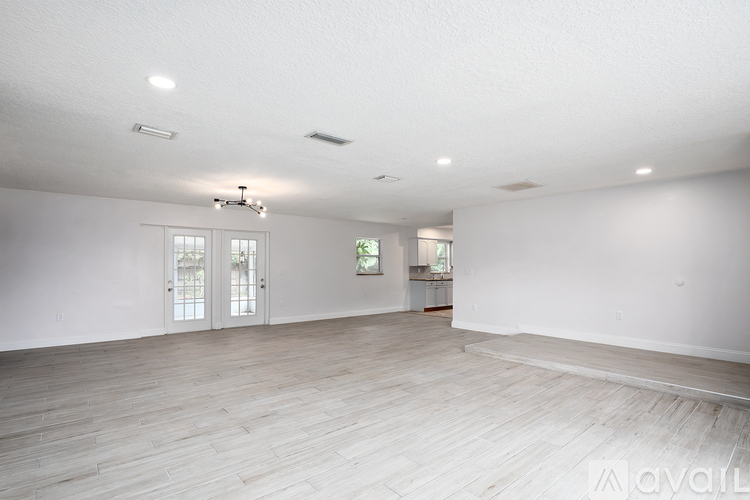 A spacious room with wooden flooring and white walls.