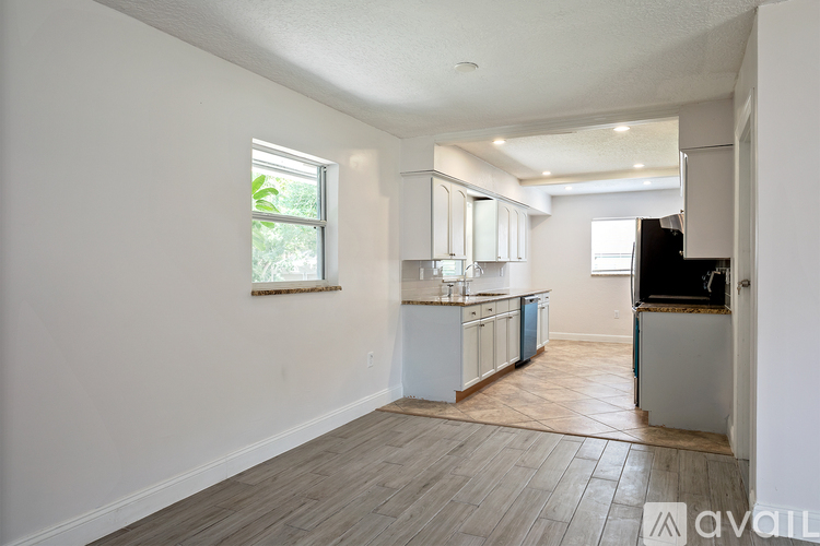 A kitchen with white cabinets and a window is available for rent.