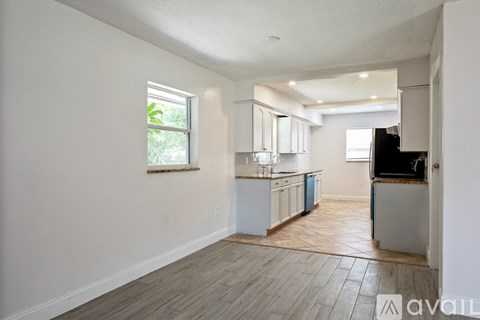 A kitchen with white cabinets and a window is available for rent.