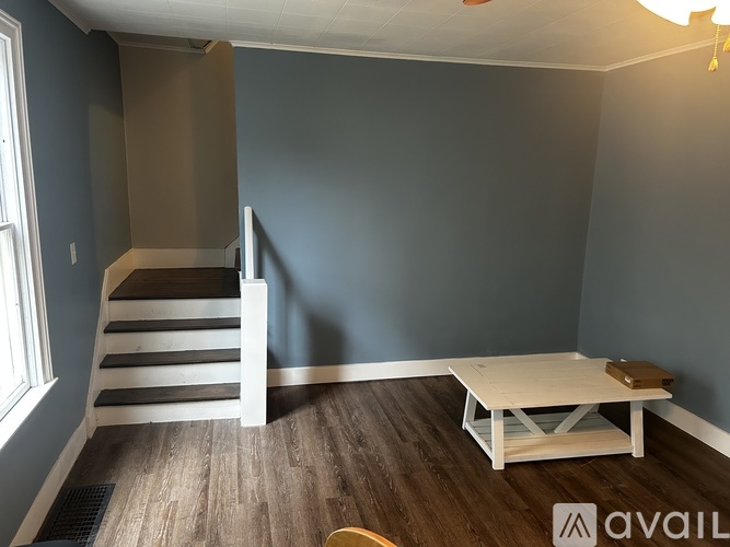 A room with a wooden staircase and a white coffee table.